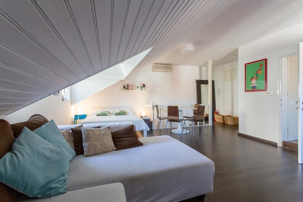 Une chambre d’hôtel moderne avec un plafond en pente, un grand lit, un bureau et une chaise.