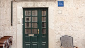 A green door with a window, a sign indicating a studio apartment, and a chair outside. - Apartment Dubravka Iza Roka (Dubrovnik)