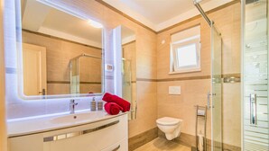 Un baño con un espejo grande, un lavabo, un inodoro y una zona de ducha.