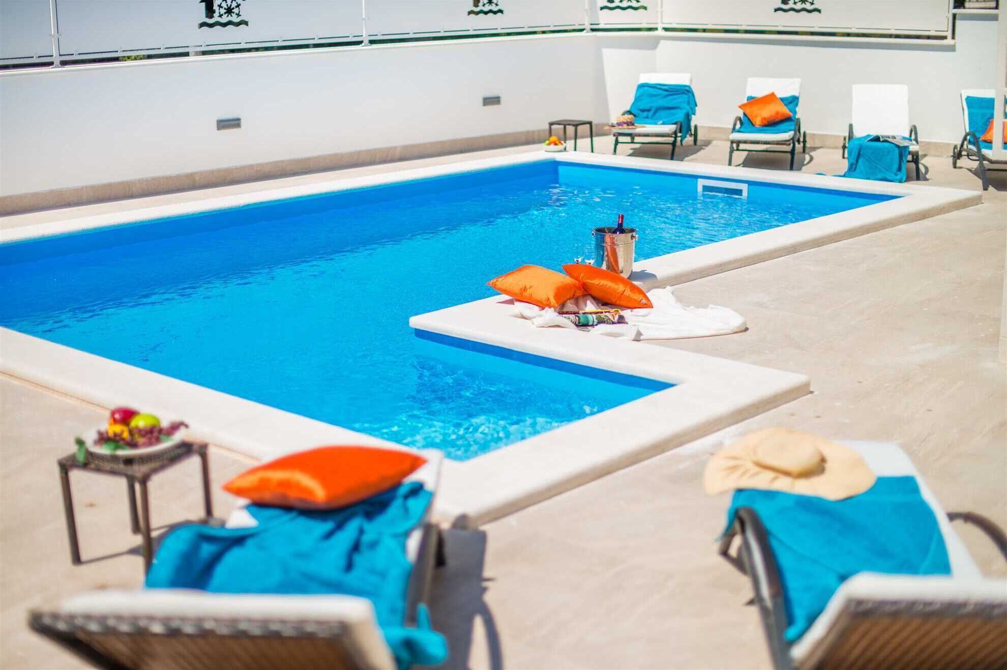 A swimming pool with lounge chairs and a bucket of items on the edge.