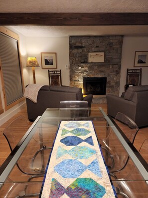 A living room with a glass-top dining table, two sofas, a stone fireplace, and framed pictures on the walls. - Cabin on Henry's Fork, stunning river views,  footpath to river, sleeps 8 (Island Park)