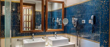 A bathroom with two sinks, a large mirror, and a hairdryer on the wall.
