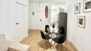 A dining area with a glass table and black chairs, a white door, and a refrigerator in the background.