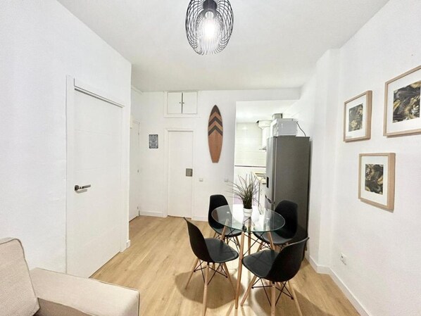 A dining area with a glass table and black chairs, a white door, and a refrigerator in the background.