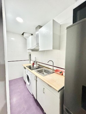 A compact kitchen with a washing machine, a sink, and a refrigerator.