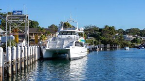 A boat docked at a marina with a sign for Jervis Bay Game Fishing Club.