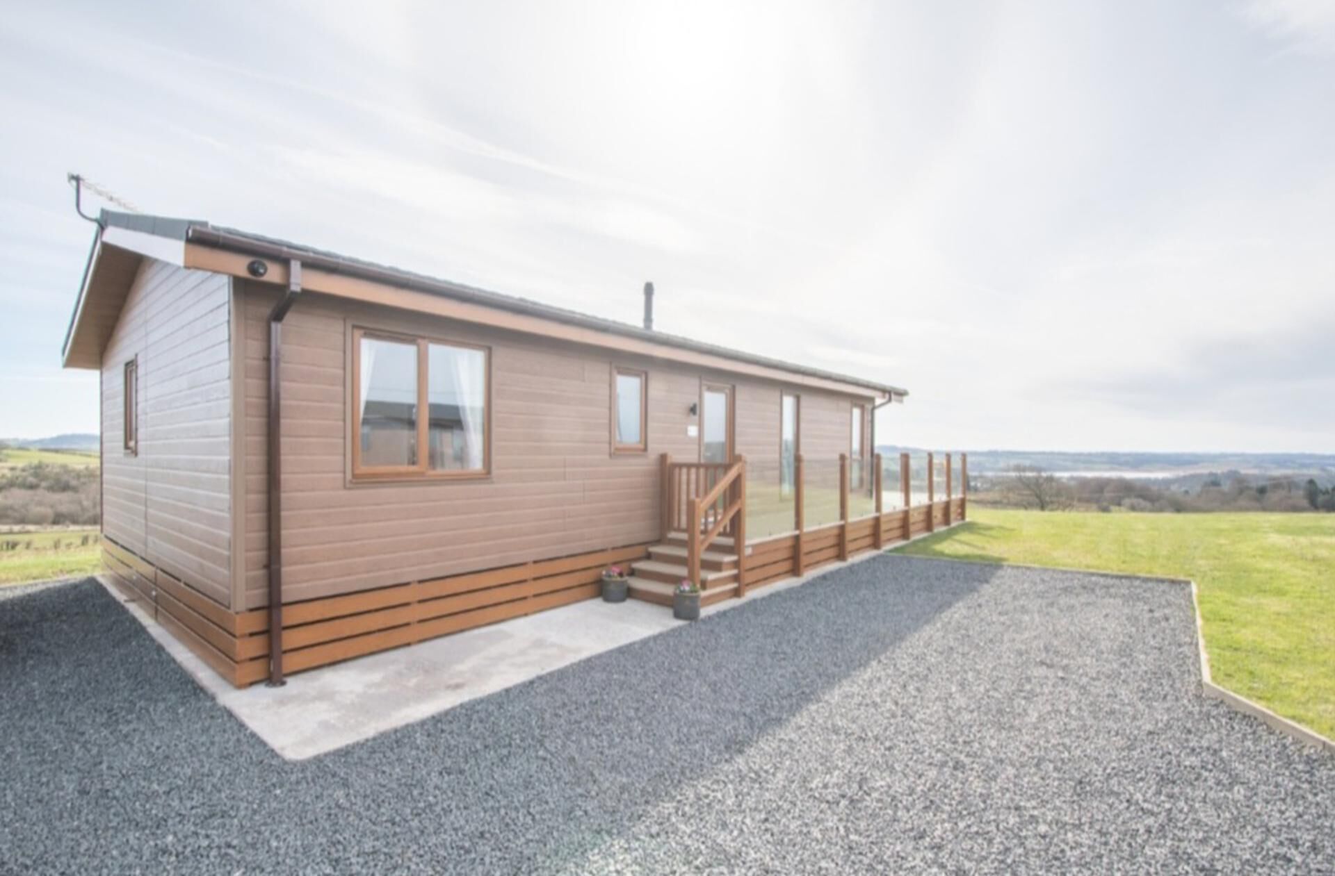Une maison mobile de plain-pied, dotée d’un porche couvert et d’une allée en gravier.