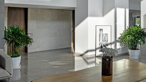 A spacious lobby with a wooden table, potted plants, and a large artwork on the wall. - Hyatt Delhi Residences (New Delhi)