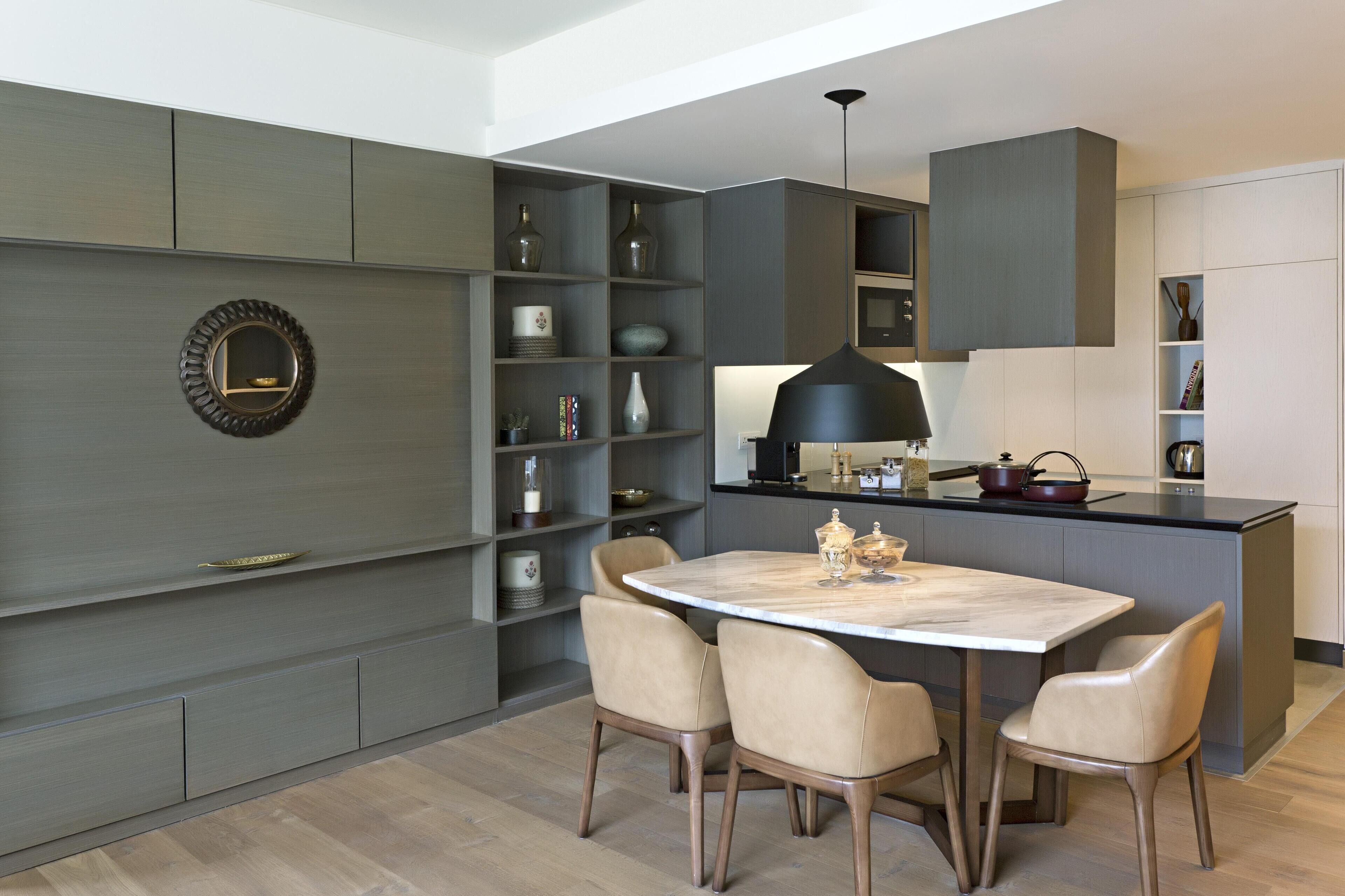 A modern kitchen with a central island, built-in shelves, and a dining area with chairs.