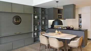 A modern kitchen with a central island, built-in shelves, and a dining area with chairs.