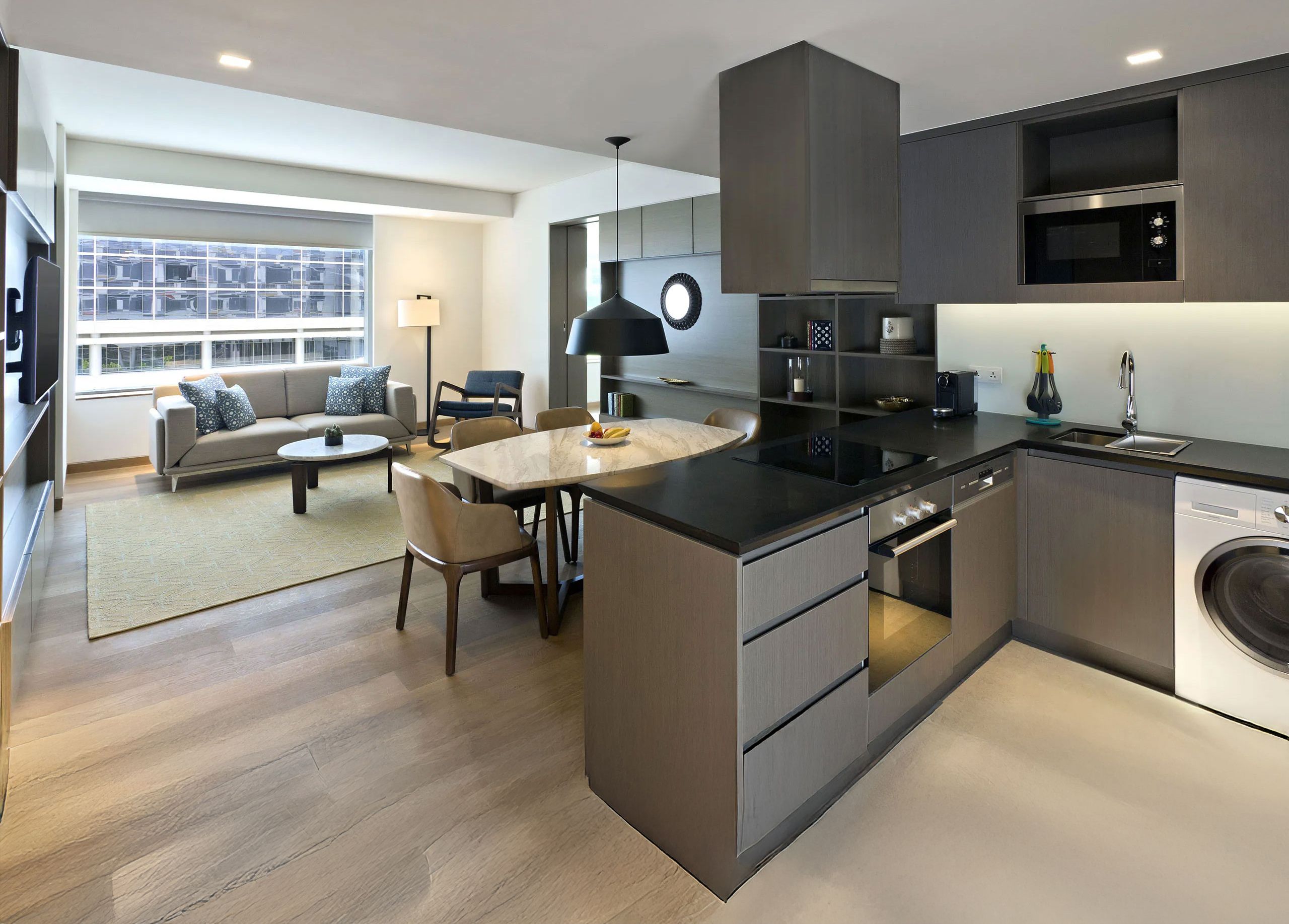 A modern kitchen with a central island, built-in appliances, and a dining area with a sofa and chairs.