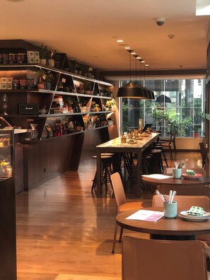 A modern restaurant interior with a bar area, dining tables, and chairs. - Hyatt Delhi Residences (New Delhi)