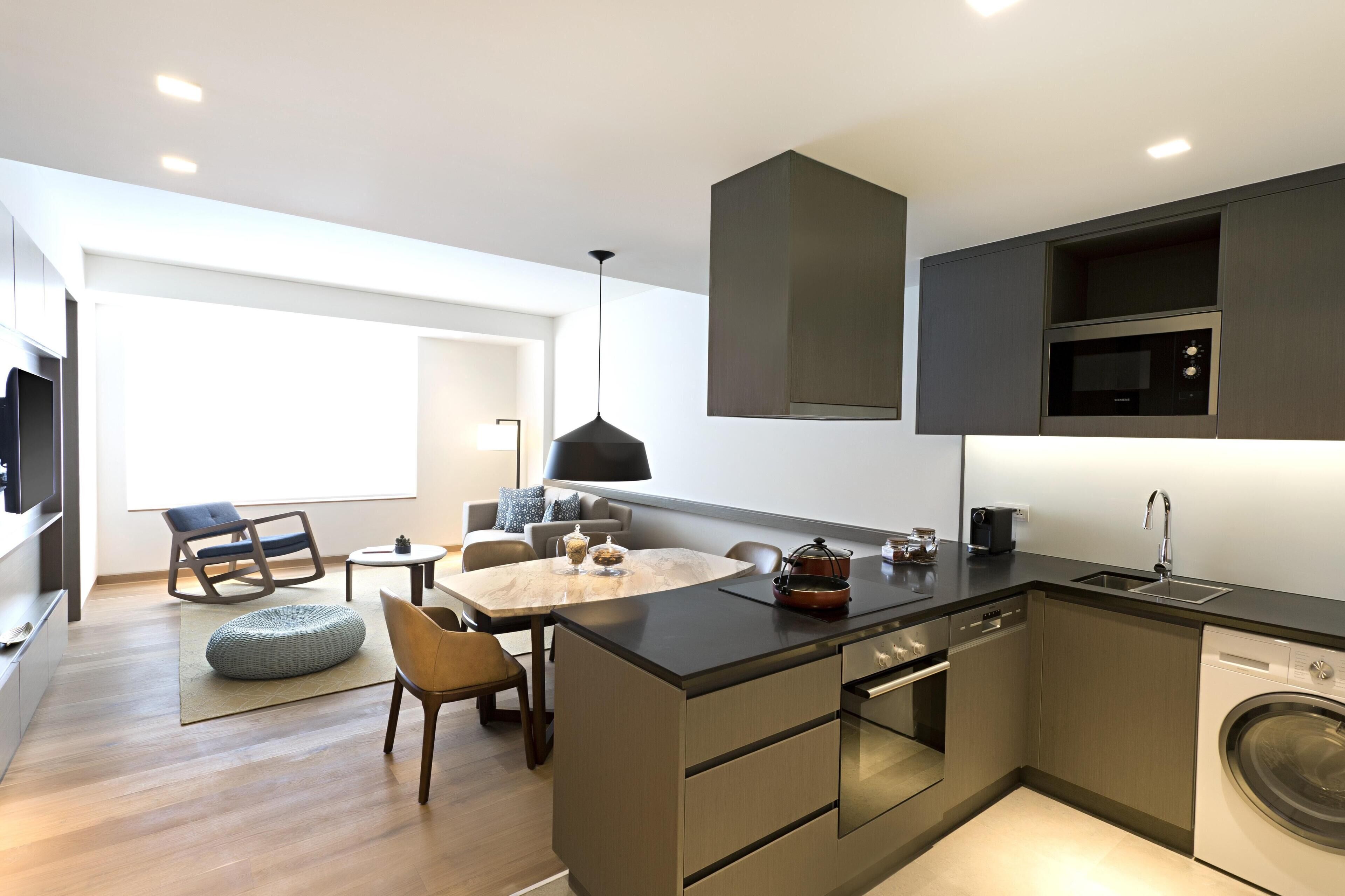 A modern kitchen with a dining area, built-in appliances, and a large window.