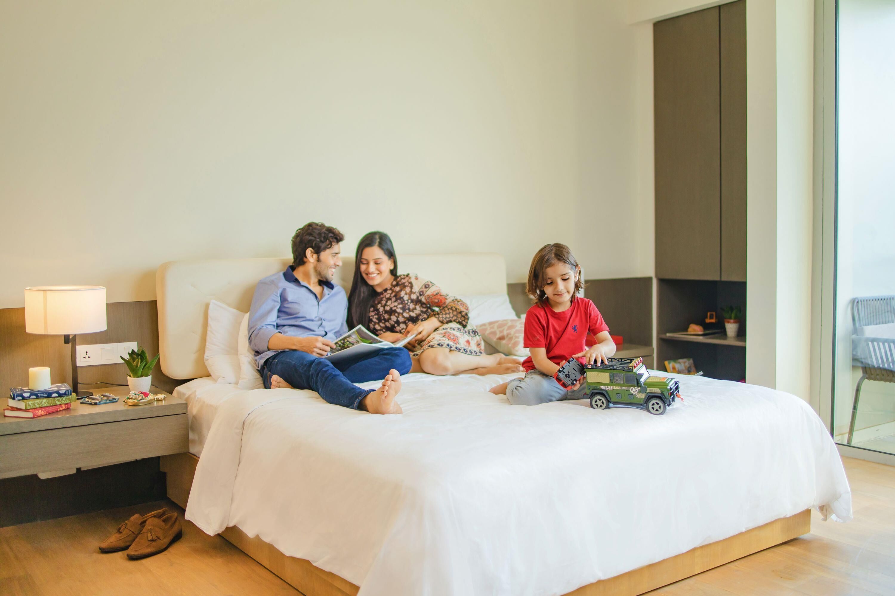 A bedroom with a bed, bedside tables, a lamp, a plant, and a toy car.