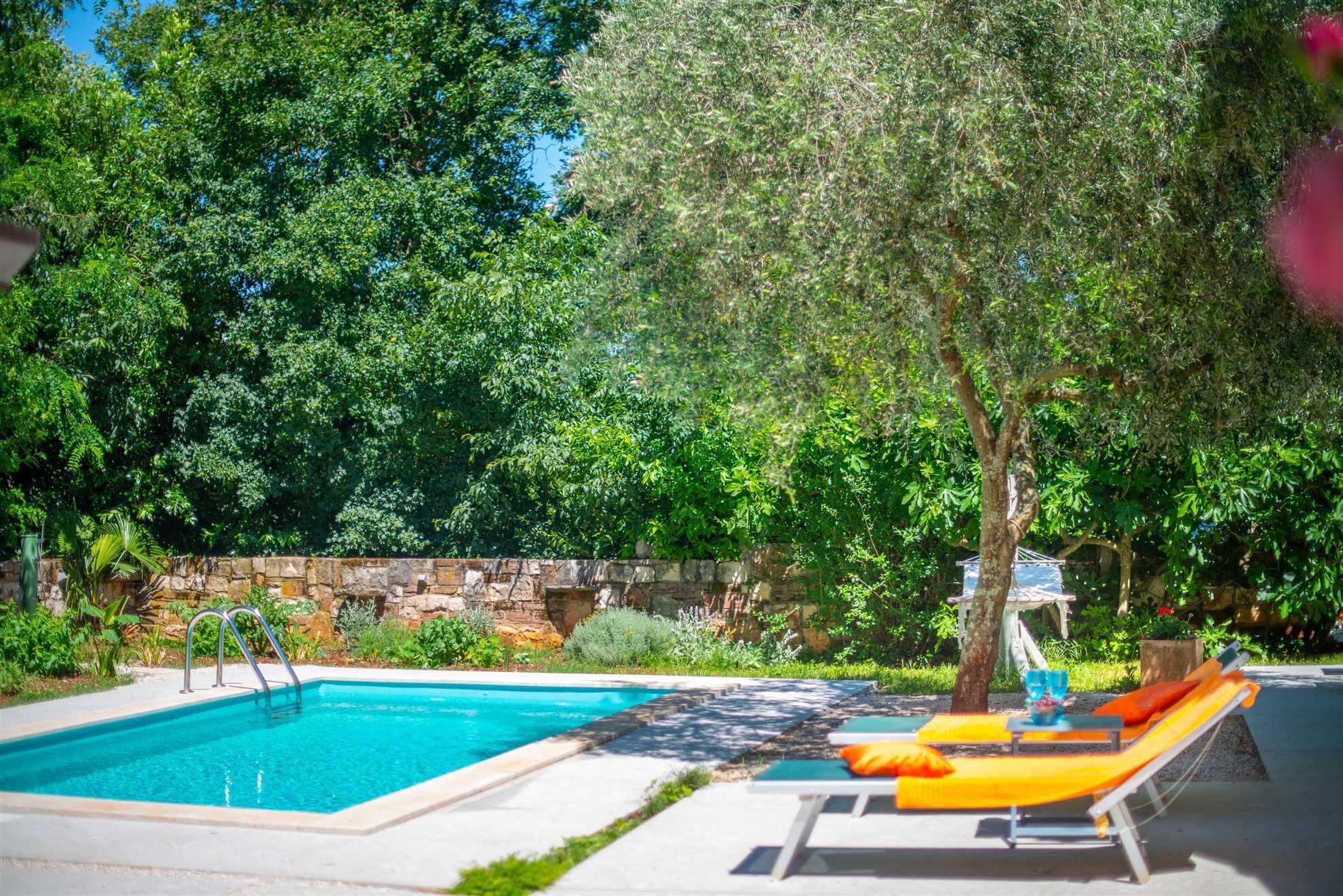 A swimming pool with lounge chairs and a stone wall.
