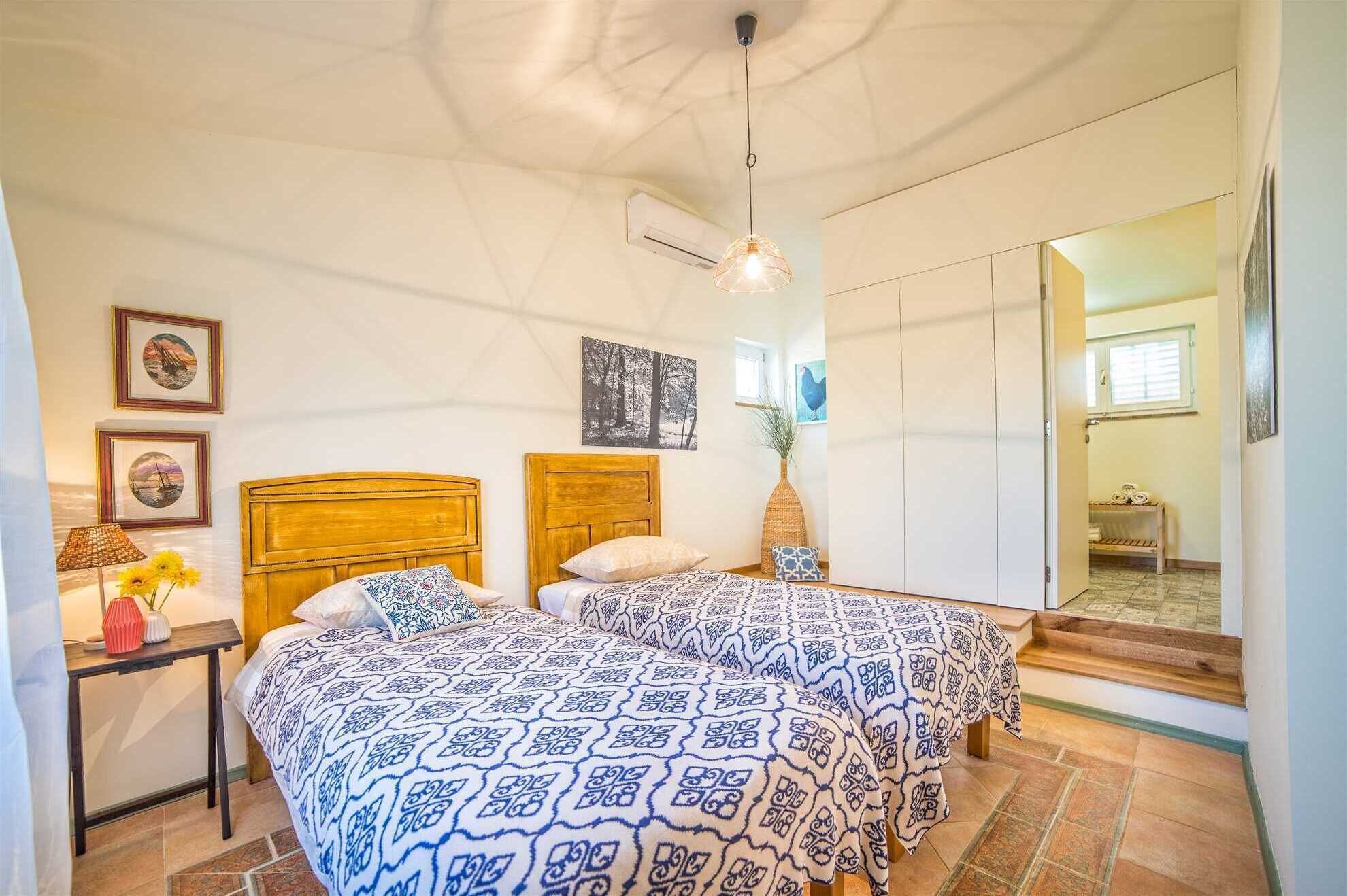 A bedroom with two beds, a nightstand, a lamp, and a window.