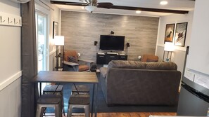 Un salon moderne comprenant un canapé, une table à manger avec des chaises, un téléviseur à écran plat et un ventilateur de plafond.