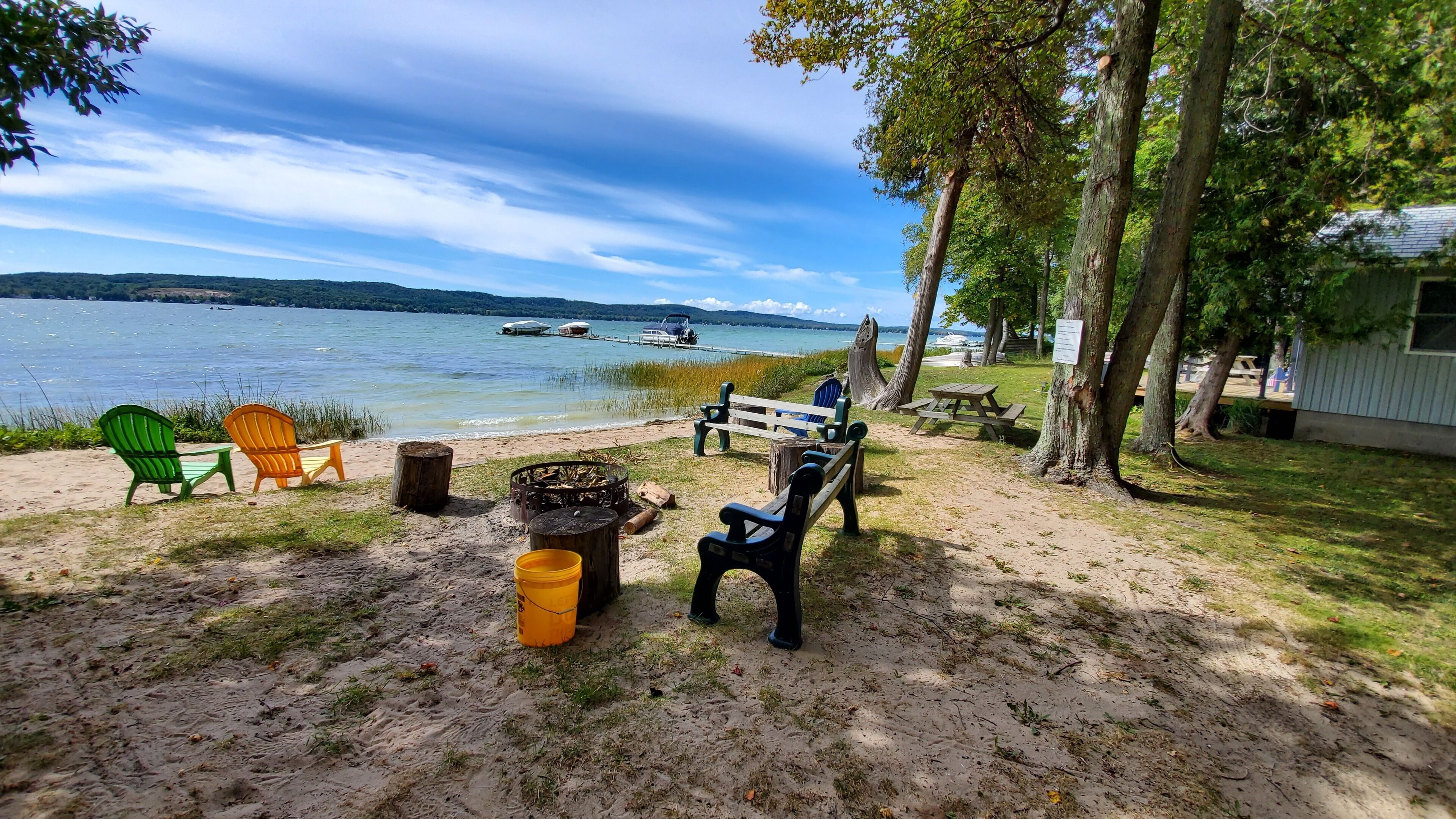 Un espace de pique-nique au bord du lac, équipé de chaises, d’un foyer et d’un banc.