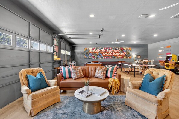 A spacious garage converted into a living area with a sofa, armchairs, and a coffee table.