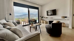 Un salon moderne doté d’une grande fenêtre, d’un téléviseur à écran plat et d’un canapé.