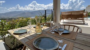Une table dressée pour deux personnes, avec vue sur les montagnes et la mer.