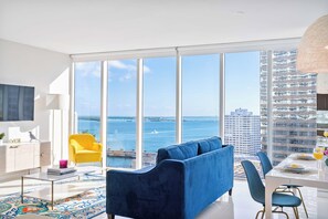 A modern living room with a large window overlooking a body of water and a cityscape. - Heart of Brickell | Spacious 2BR Near City Centre (Miami)