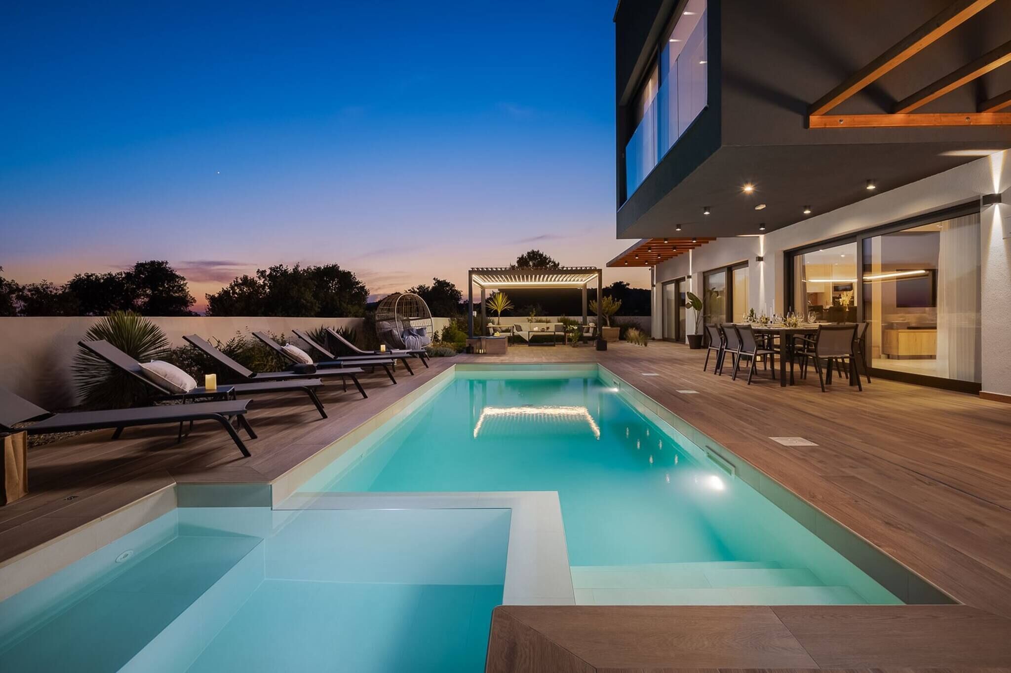 A rooftop pool area with lounge chairs, a pergola, and a dining area.
