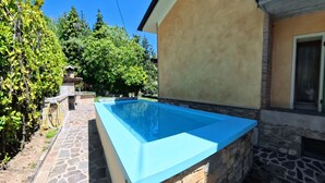 A swimming pool adjacent to a stone wall, with a stone pathway leading to a house with a balcony. - Villa Arianna – Panorama Suite, Lake Garda view apartment with pool (Tignale)