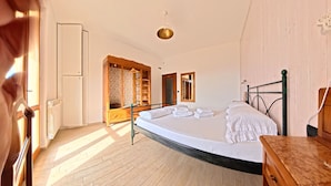 A bedroom with a bed, wooden wardrobe, and a radiator. - Villa Arianna – Panorama Suite, Lake Garda view apartment with pool (Tignale)
