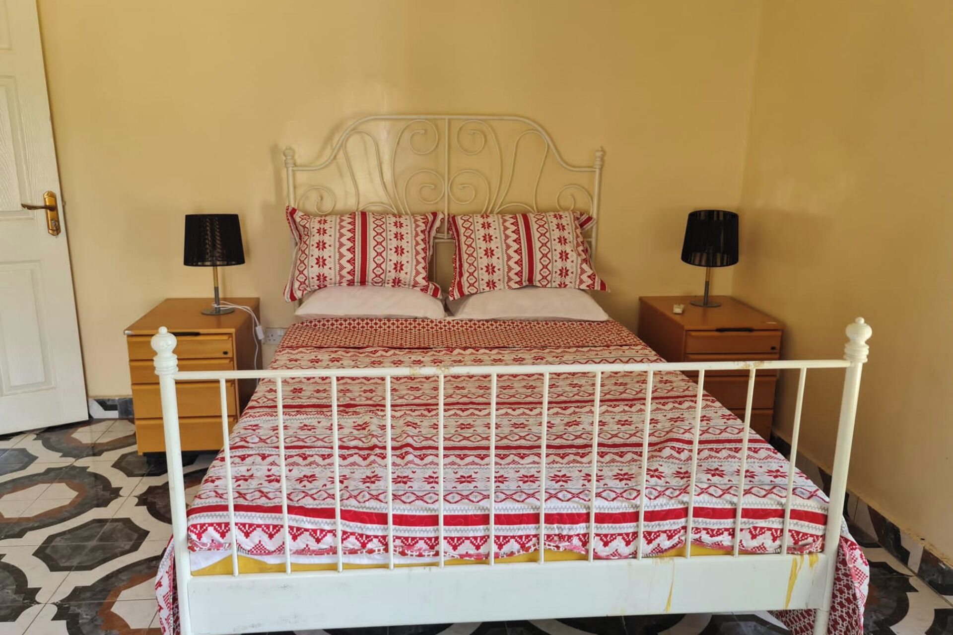 A bed with a metal frame, two bedside tables, and patterned bedding.