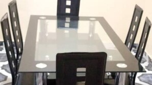 A rectangular glass-top table with four chairs around it. - 4 Bed House Sleeps 8 - Garden and Pets Welcome (Brikama)