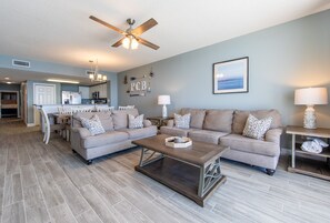 A spacious living room with two sofas, a coffee table, and a ceiling fan.