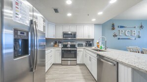 Une cuisine moderne dotée d’appareils électroménagers en acier inoxydable, de meubles blancs et d’un mur d’accent bleu.