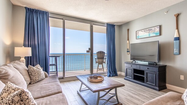 Un salon comprenant un canapé, une table basse, un téléviseur à écran plat et un balcon avec vue sur l’océan.