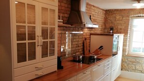 Una cocina con armarios de madera, pared de ladrillo y ventana.