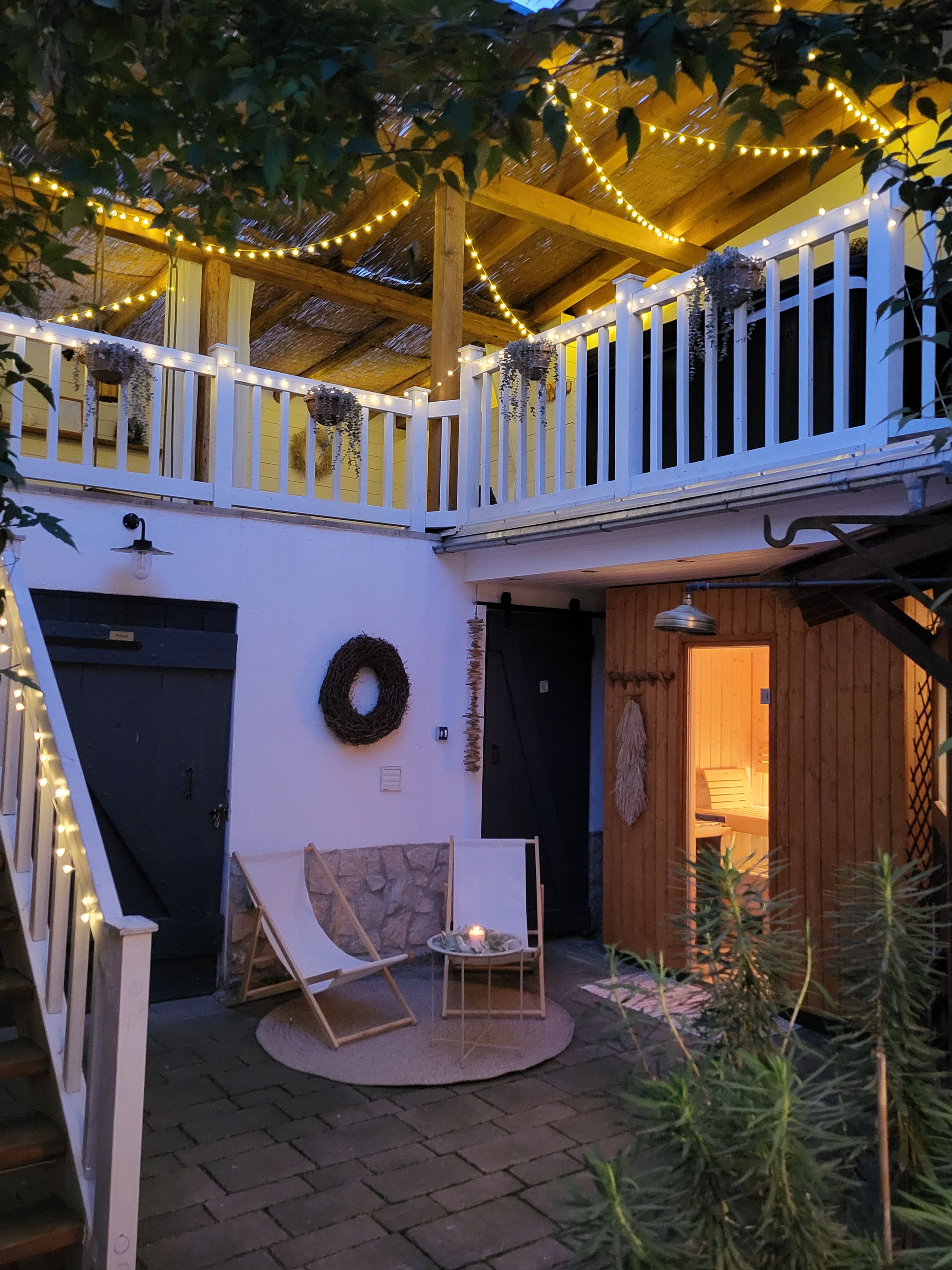 A covered outdoor area with a wooden deck, string lights, and a seating arrangement.
