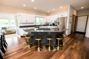 A modern kitchen with white cabinets, a central island with stools, and stainless steel appliances. - NEW LISTING. Beautiful Alexandria DREAM home perfect for families and friends! (Alexandria)