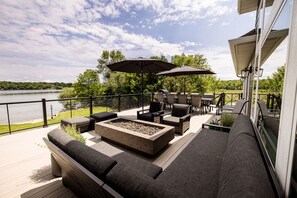 A deck with outdoor furniture, a fire pit, and umbrellas overlooking a body of water. - NEW LISTING. Beautiful Alexandria DREAM home perfect for families and friends! (Alexandria)