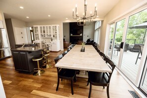 Una cocina moderna con una isla central, taburetes de bar y un comedor con una mesa grande y sillas.
