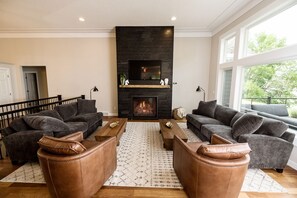 A modern living room with a fireplace, two sofas, a coffee table, and a large window. - NEW LISTING. Beautiful Alexandria DREAM home perfect for families and friends! (Alexandria)