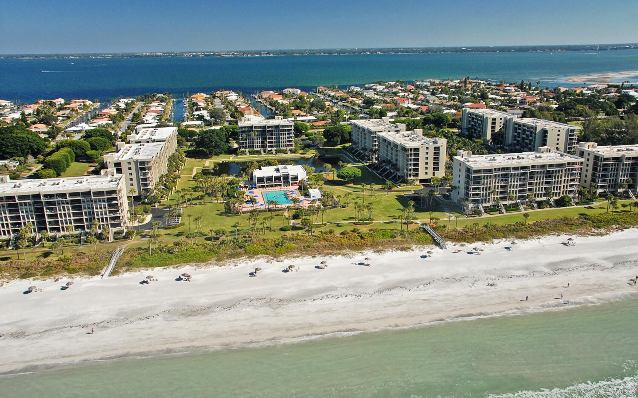 Een hotelcomplex aan de kust met meerdere gebouwen, een zwembad en een strand.