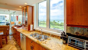 A kitchen with granite countertops, stainless steel appliances, and a view of the ocean. - Great Beach View 2 Bedroom Condo (Longboat Key)