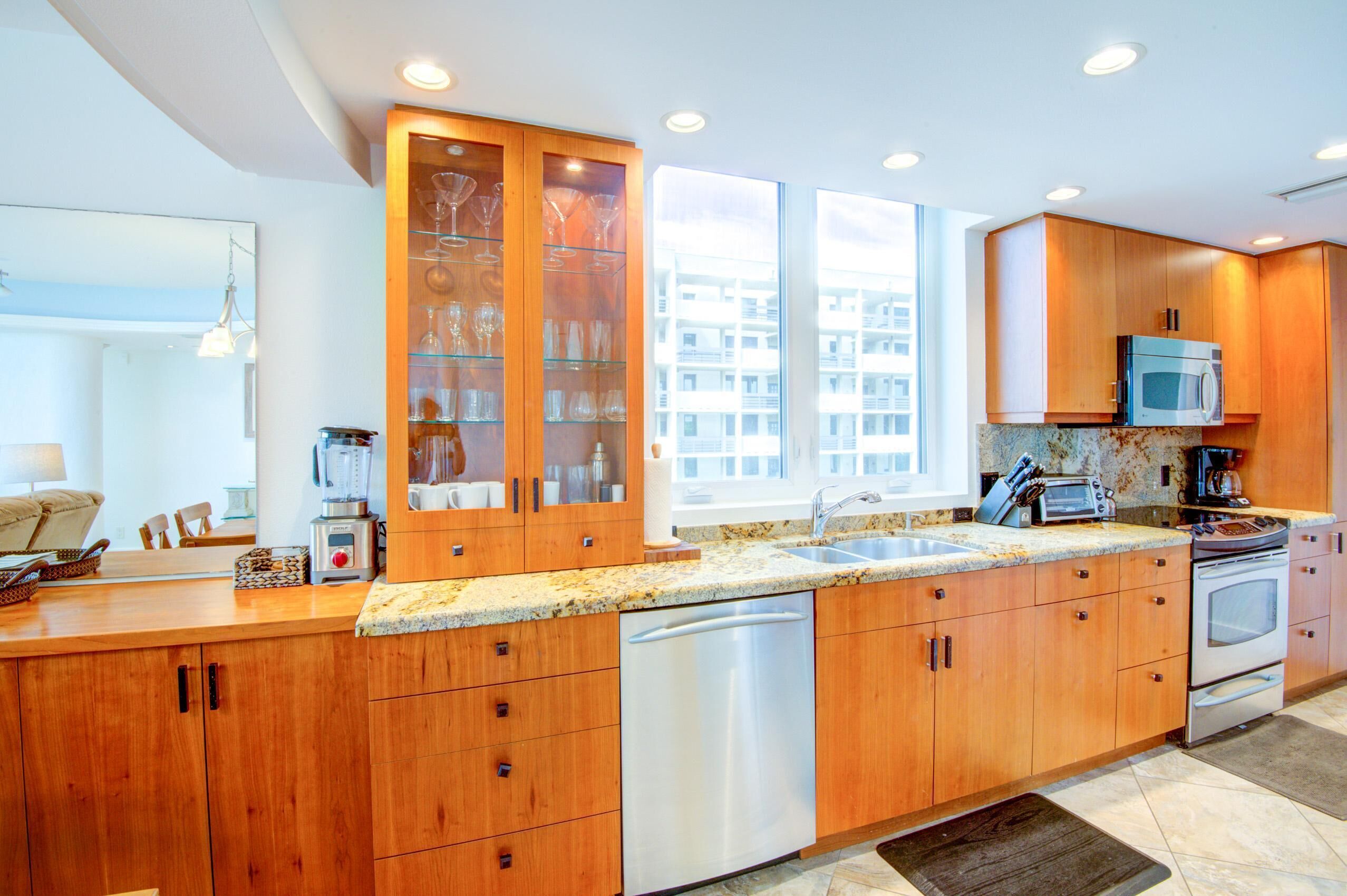 A modern kitchen with wooden cabinets, stainless steel appliances, and a granite countertop.