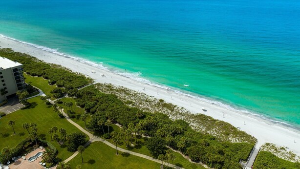 An aerial view of a beach with a hotel and lush greenery. - Great Beach View 2 Bedroom Condo (Longboat Key)