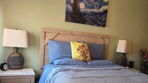 Ein Schlafzimmer mit einem Bett, zwei Nachttischen, einer Lampe, einer Uhr und einem Bild an der Wand.