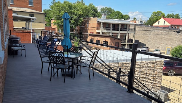 Eine Holzterrasse mit Sitzgelegenheiten und Blick auf Gebäude im Hintergrund.