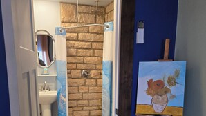 Ein Badezimmer mit Dusche, Toilette und Waschbecken. Ein Gemälde steht auf einem Staffelei.