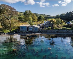 A lakeside property with stone buildings, clear water, and surrounding greenery. - Mulroe Cove - House (Dunbeacon,)