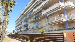 Un immeuble résidentiel à plusieurs étages, doté de balcons, d’une clôture en bois et de palmiers.