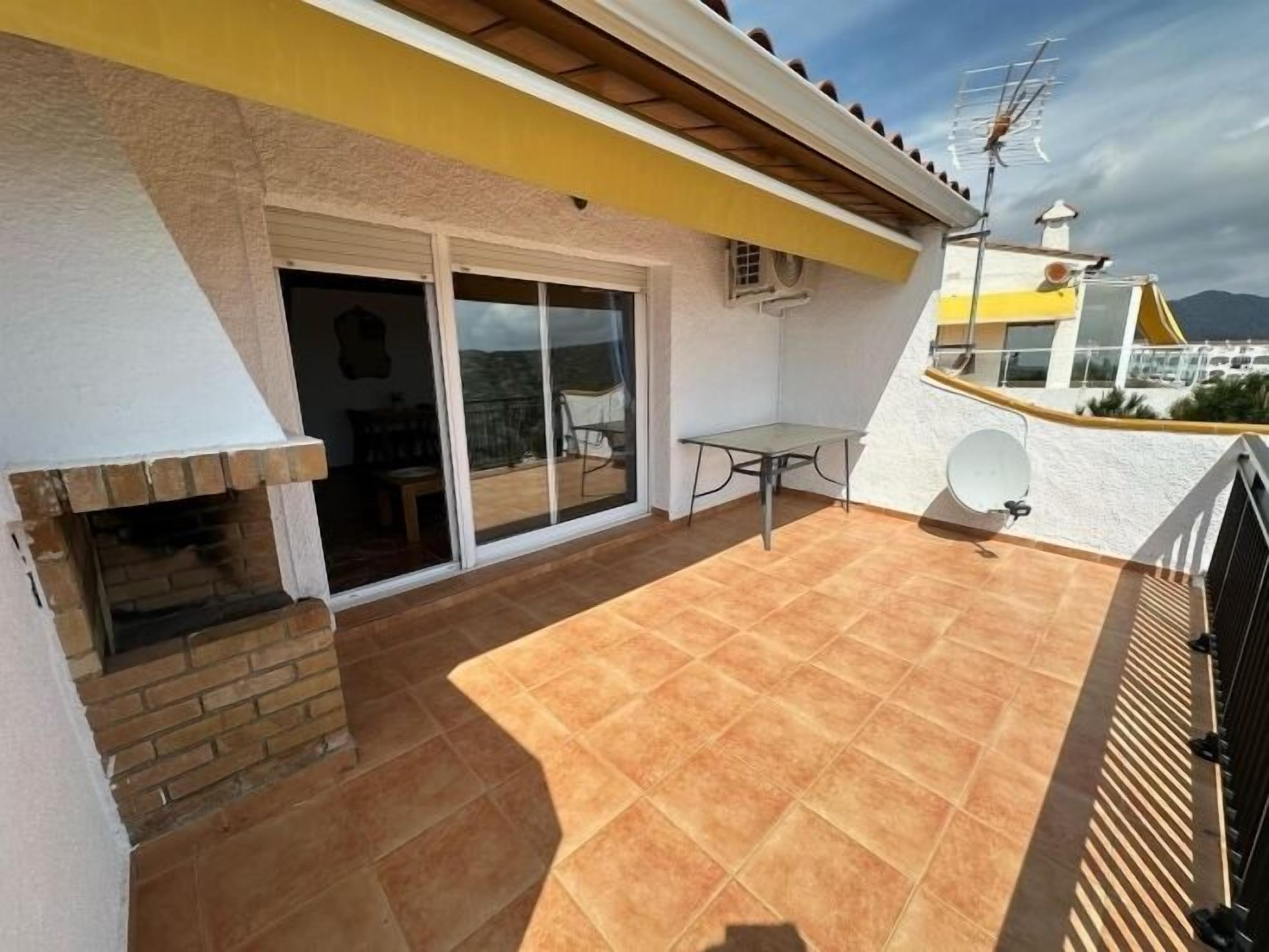 A patio with a brick fireplace, a table, and a sliding glass door leading to an indoor area.